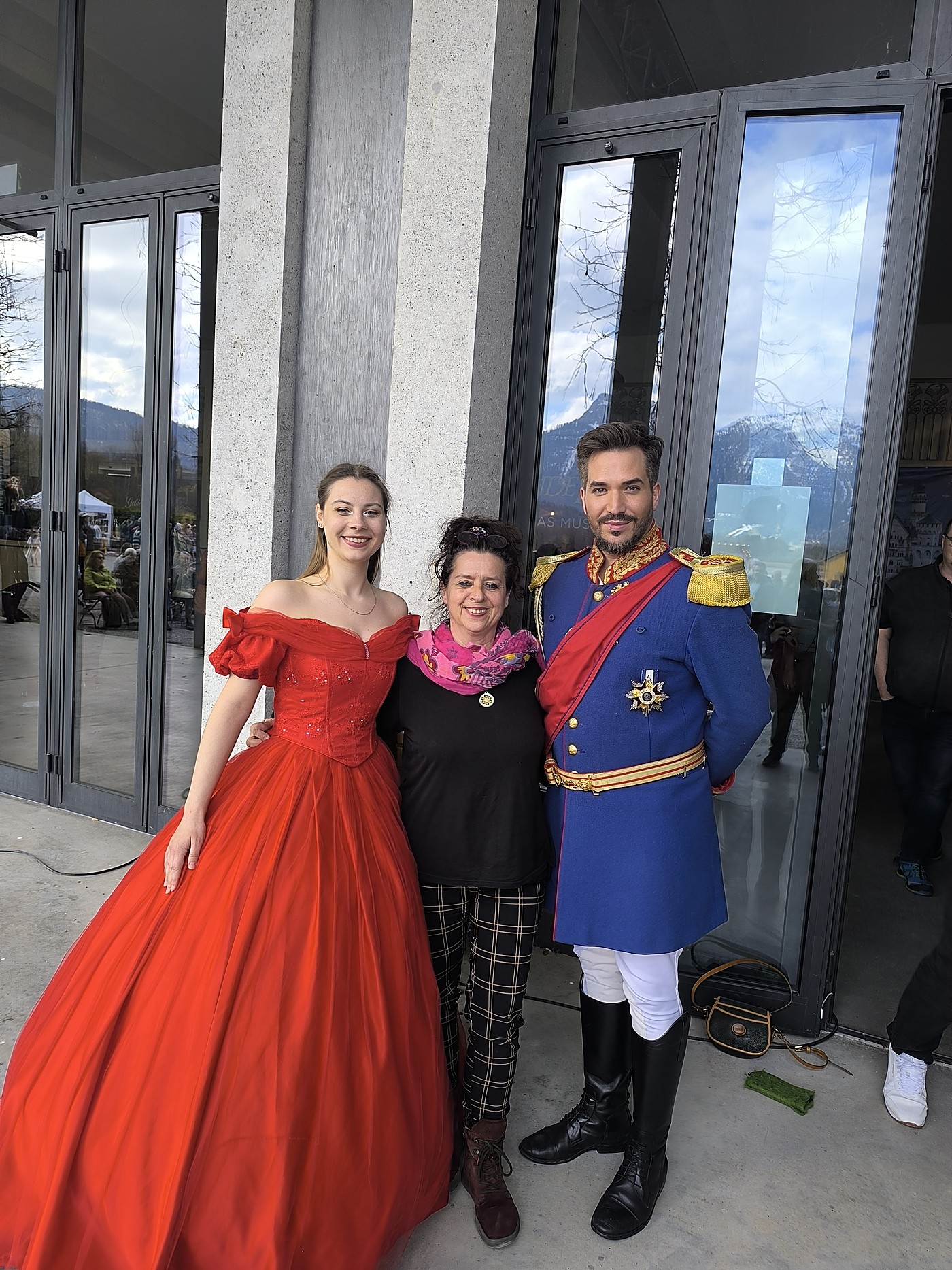 Annette Löchner mit zwei kostümierten Darstellern vor einem Theater
